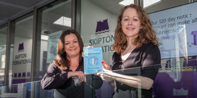 people smiling in front of Skipton office with award