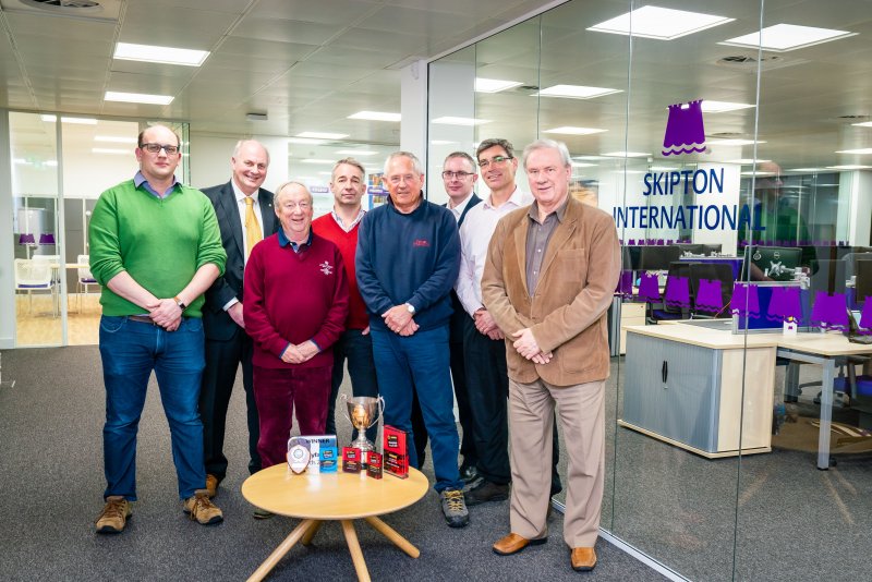 people smiling in front of Skipton logo