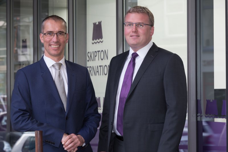 Two men in front of Skipton International Limited building