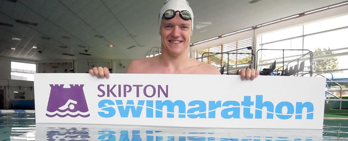 Person in water holding Swimarathon sign