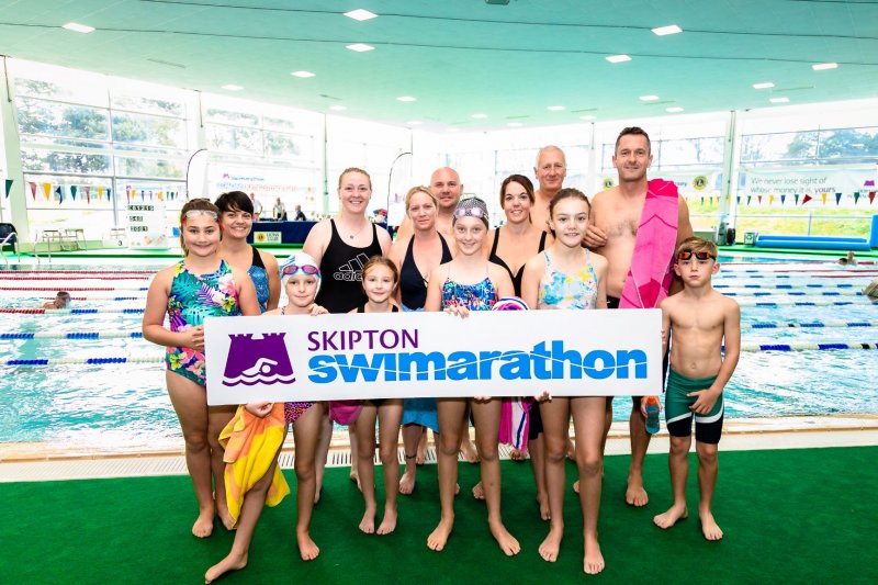 Group of swimmers posing with Skipton Swimarathon logo