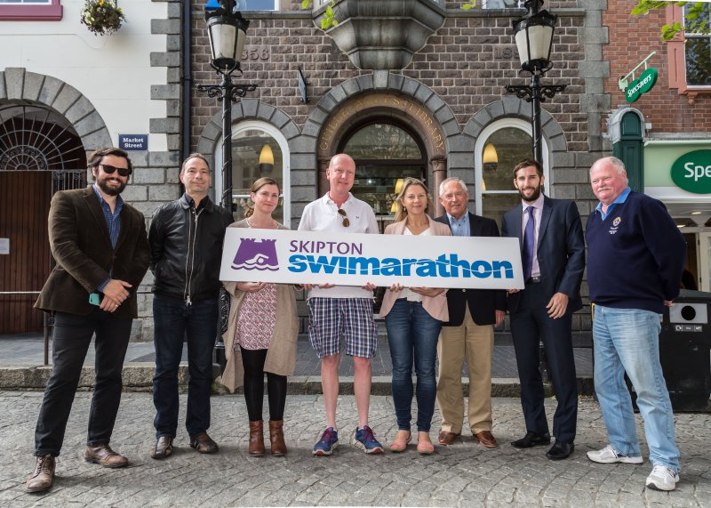 people smiling in front of Skipton Swimarathon logo