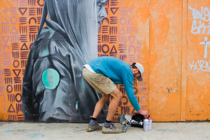 Man bending over to pick up spray paint