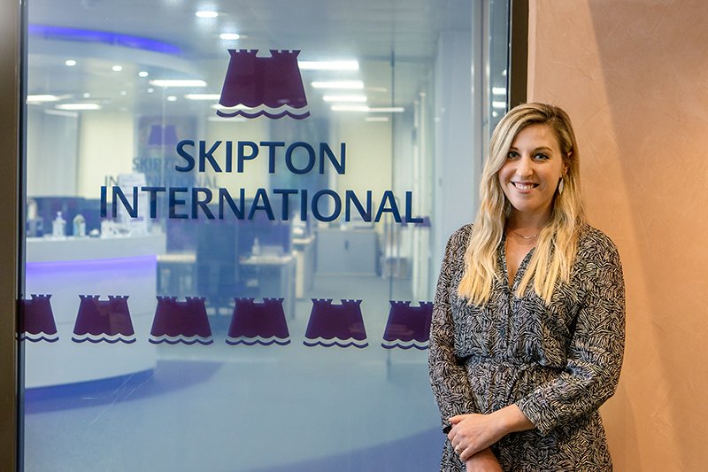 person standing in front of skipton international logo
