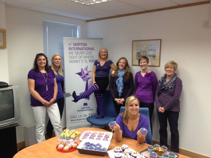 People in front of Skipton International Limited banner