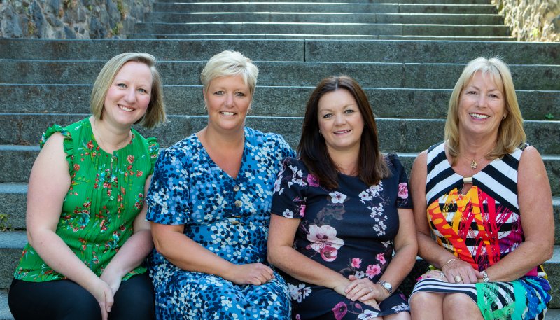 four women smiling on stone stairs