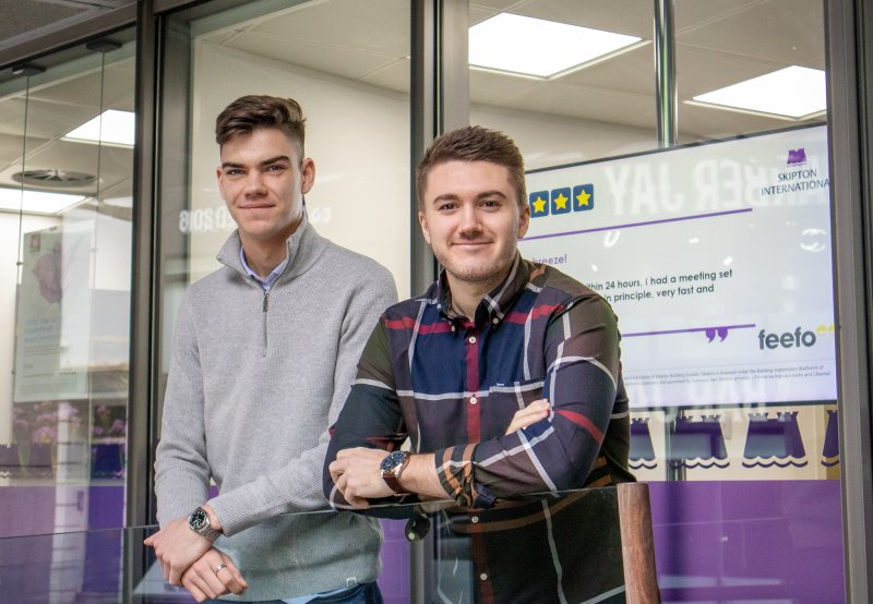 people smiling in front of Skipton logo